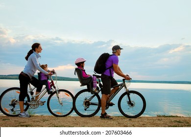 Young family with two kids go for a cycle ride on the beach at background sunset - Powered by Shutterstock