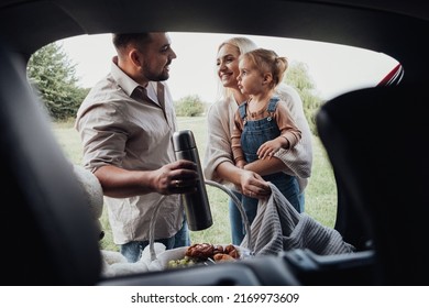 Young Family, Two Parents with Their Little Kid Preparing to Picnic Time Outdoors, View Through the Open Trunk of SUV Car - Powered by Shutterstock