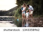 A young family with two toddler children outdoors by the river in summer.