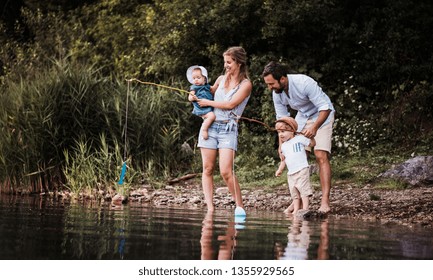 A young family with two toddler children outdoors by the river in summer. - Powered by Shutterstock