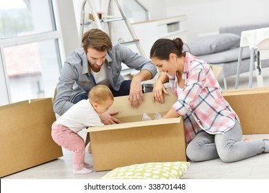 Young Family Unpacking Boxes In New Home