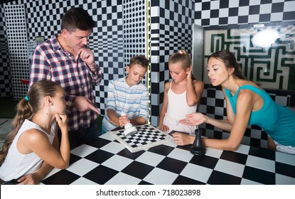 Young Family Is Visiting Of Escape Room Stylized Under Chessboard.