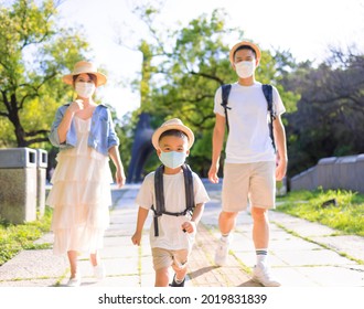 Young Family Wearing The Medical Mask And Walking In The Park