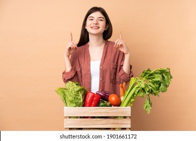 Young farmer girl with freshly picked vegetables in a box pointing up a great idea