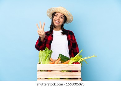 Young Farmer Woman Holding Fresh Vegetables In A Wooden Basket Happy And Counting Three With Fingers