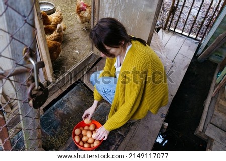 A young farmer woman holds fresh eggs in her hands in a chicken coop