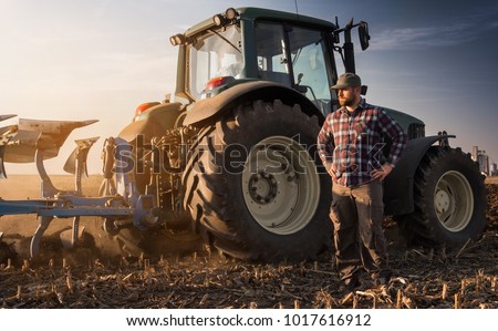 Young farmer working during the tractor plowing fields -preparing land for sowing