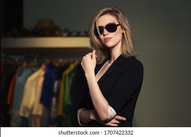 Young fashion blond business woman in the mall  Stylish female model in black blazer and sunglasses