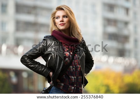 Young fashion blond woman in leather jacket on the city street