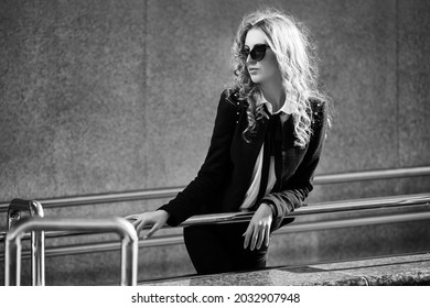 Young Fashion Blonde Business Woman Leaning On Railing Stylish Female Model In Black Jacket And Sunglasses 