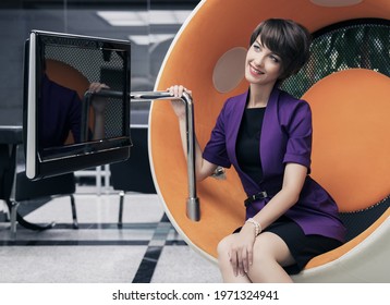 Young Fashion Business Woman Sitting On Computer Chair In Office Stylish Female Model In Purple Blazer With Pixie Hair Style