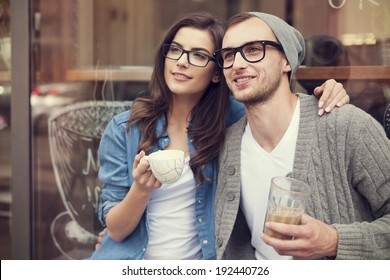 Young fashion couple drinking coffee outside of cafe 