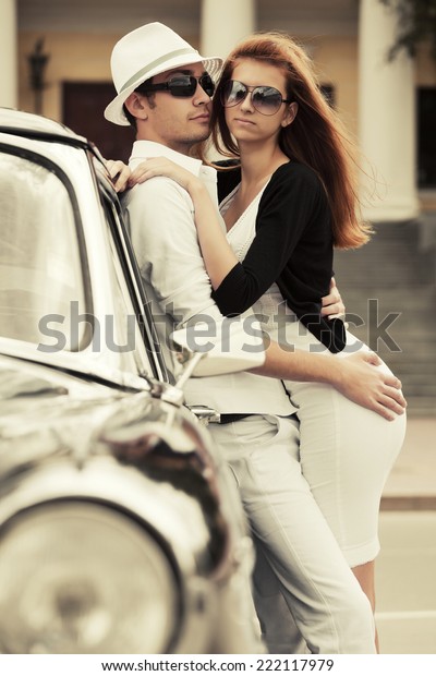 Young fashion\
couple in love at the retro car\

