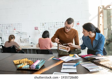 Young fashion designers choosing colors and textile for new collection against two women sewing - Powered by Shutterstock