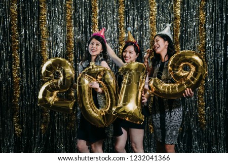 young fashion girls wearing party hats celebrating happy New Year eve at nightclub. group of friends dancing with 2019 gold balloons enjoy music. clubbing ladies love night lifestyle concept.