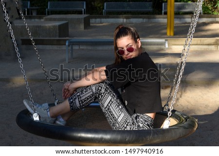 Young fashion hipster woman sitting on the swing.