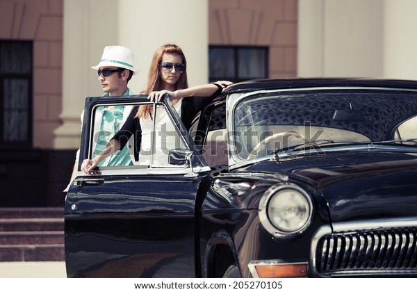 Young fashion man\
and woman at the retro car\
