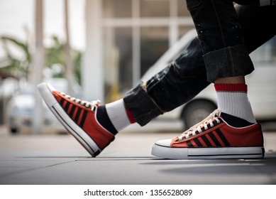 Young fashion man's legs in blue jeans and orange sneakers on green grass. - Powered by Shutterstock