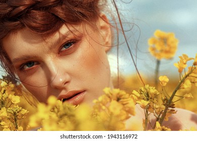  Young fashion model portrait with ginger hair and blue eyes in yellow rapeseed field - Shutterstock ID 1943116972