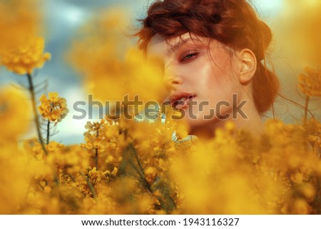  Young fashion model portrait with ginger hair and blue eyes in yellow rapeseed field