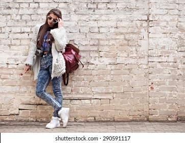 Young fashion woman flirting on the background of old brick wall. Outdoors, lifestyle.