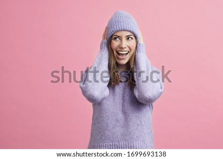 Young fashion woman looking cute with sweater and matching hat on colorful background ready for winter