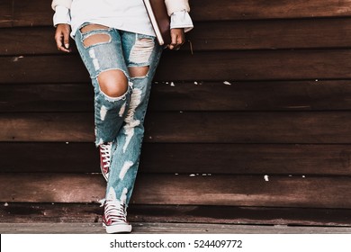 Young fashion woman's legs in jeans and shoes on wooden floor