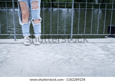Young fashion woman's legs in ripped jeans and sneaker shoes