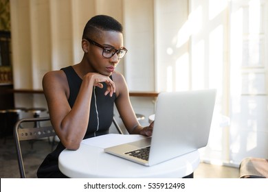 Young Fashionable African Business Woman Working Hard At The Cafe On The Laptop