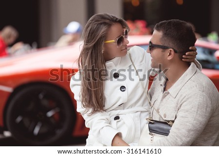 Young fashionable couple in love outdoor. Couple embracing, wife sitting on her husband lap.