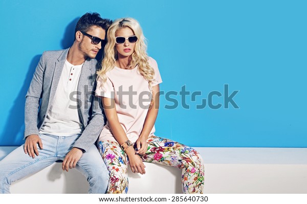 Young fashionable\
couple on blue background