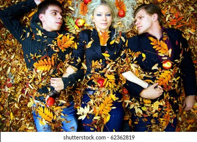 Young Fashionable People In Autumn Park. Resting On Red Dry Leaves. Sin Of Desire Concept