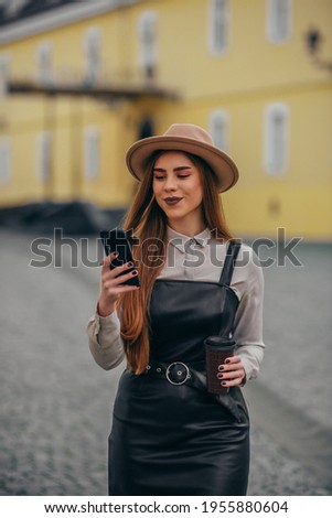 Young fashionable woman using a smartphone while walking outside