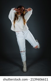 Young Fashionista In White Jeans And With A Bare Belly Posing Against Dark Wall