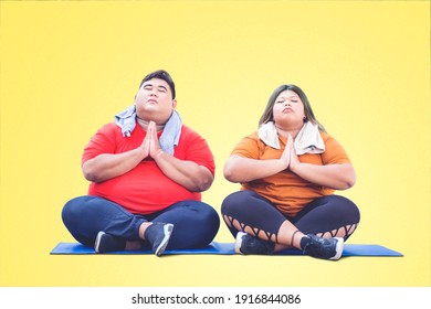 Young Fat Couple Wearing Sportswear And Doing Yoga Exercise Together While Meditating In The Studio With Yellow Background