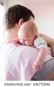Young father burping his newborn daughter, holding her affectionately. Lifestyle shoot with natural light and shallow depth of field.
