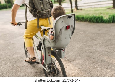 A Young Father Carries His Little Son In A Bicycle Seat. Dad And Son Ride A Bike. Child Safety Concept