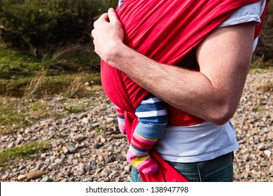 Young Father Carrying A Baby Girl In A Carrier Sling