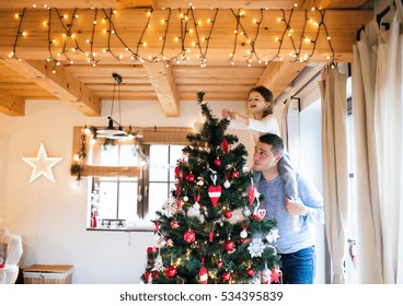 Young father with daugter decorating Christmas tree together. - Powered by Shutterstock