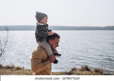 Young Father And Her Son Having Fun In The Early Spring On Lake Beach In Nature In The Park.