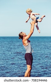 Young Father And His Baby Boy Playing. Dad With Kid On Sea Side. Man Throwing Child Up On Beach In Northern Europe.