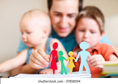 Young father and his kids holding figures of multicolored paper family - Powered by Shutterstock