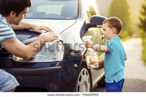 Young father with
his little son washing
car