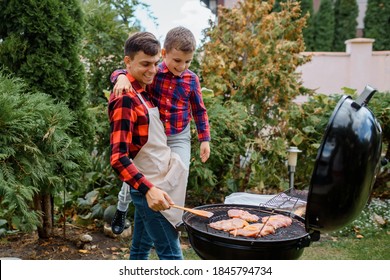 Young father and his son are cooking barbecue on an outdoor grill in their home backyard and having fun. Happy family concept - Powered by Shutterstock