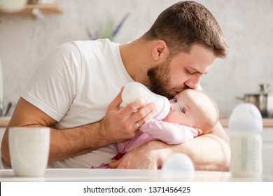 Young father kiss his baby during drinking milk - Powered by Shutterstock