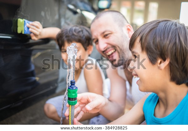 Young
father and little boys washing car in summer
day