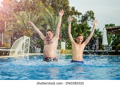 Young Father With Little Son Swimming In Pool. Cute Teenage Boy And His Father Jump And Have Fun In Swimming Pool. Happy Family Holiday Concept.