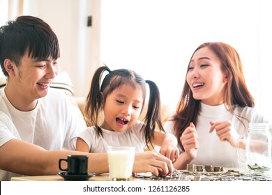 Young Father And Mother Teaching Their Kids To  Saving Money To Piggy Glass Bank 