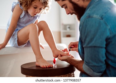 Young father painting small daughter's nails in a bathroom at home.