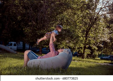 Young Father Playing With His Daughter On The Bean Bag In The Park